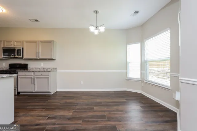 a kitchen with granite countertop a stove a sink and white cabinets with wooden floor next to windows