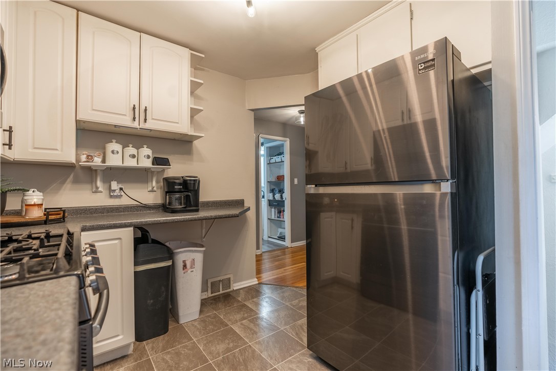 8320 Ackley Road Parma, OH 44129 - Photo 25 of 36 Kitchen featuring white cabinetry, gas range oven, dark tile flooring, and stainless steel fridge