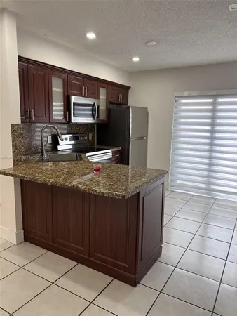 a kitchen with kitchen island granite countertop a sink and a stove top oven with wooden floor