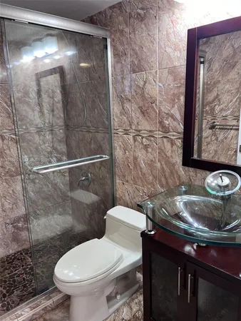 a white toilet sitting next to a bathroom sink and a shower