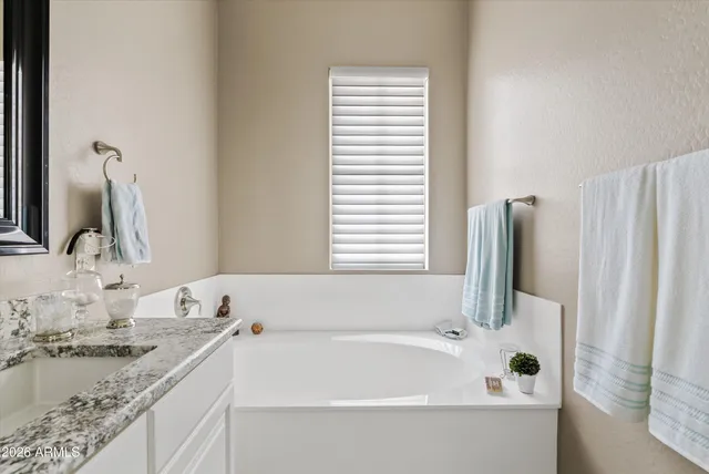 a bathroom with a granite countertop sink and a bathtub