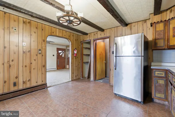 a view of a refrigerator in kitchen and an empty room