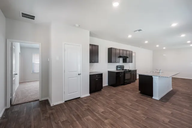 a large kitchen with a center island wooden floor and stainless steel appliances