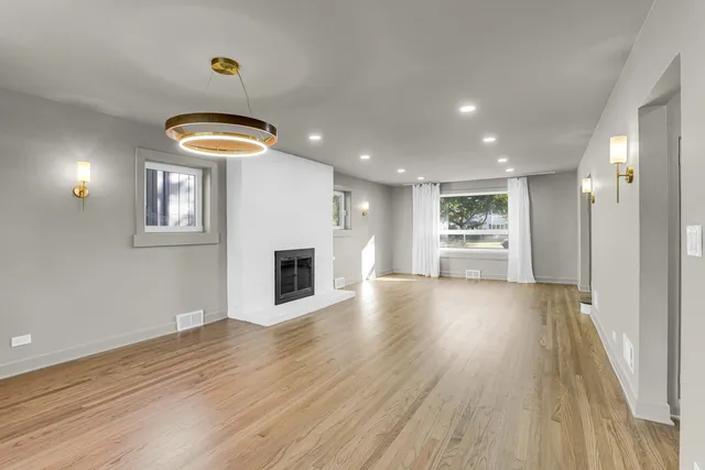 an empty room with wooden floor a fireplace and windows