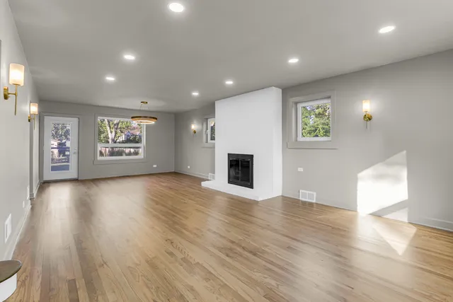 a view of an empty room with a fireplace and wooden floor