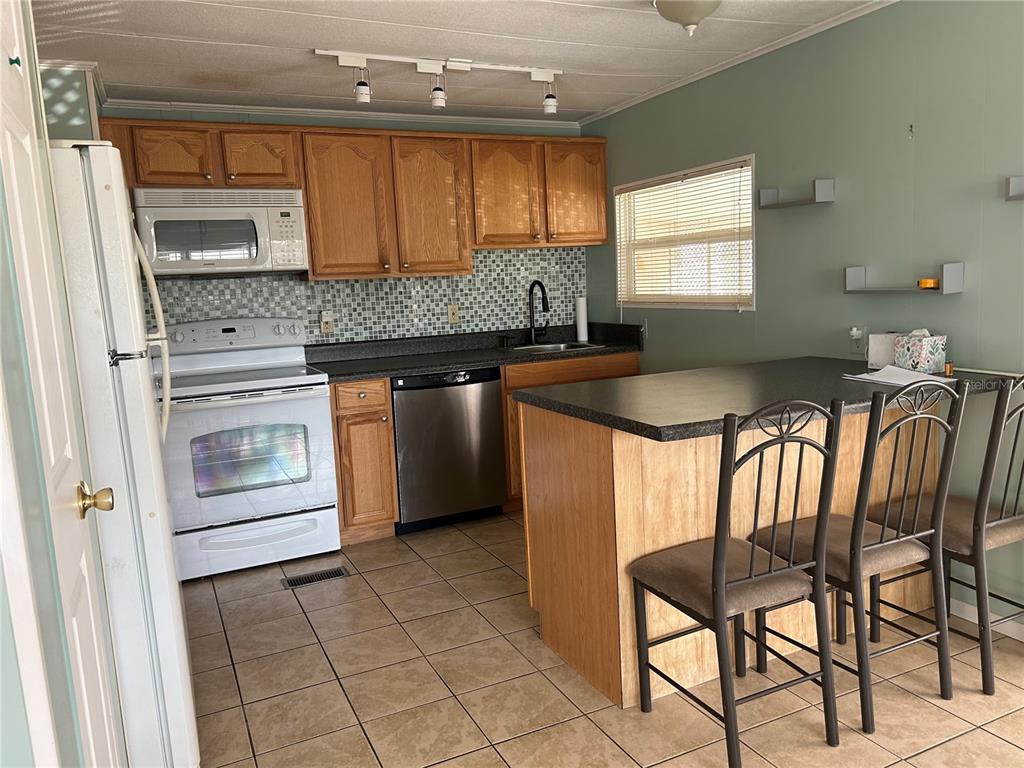 12501 Ulmerton Road, Unit 119 Largo, FL 33774 - Photo 7 of 15 a kitchen with a stove a sink and a refrigerator