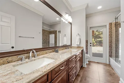 a spacious bathroom with a granite countertop double vanity sink a mirror and a bathtub