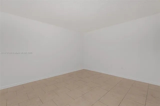 a view of a refrigerator in kitchen and an empty room