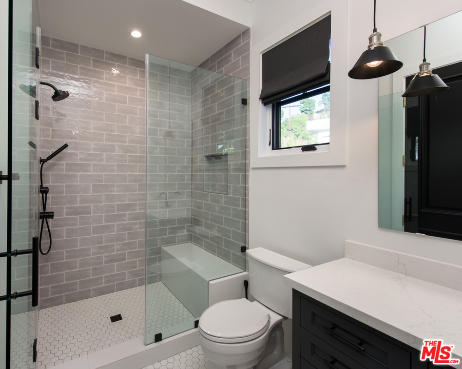16656 Oldham Street Encino, CA 91436 - Photo 32 of 46 a bathroom with a shower a toilet a sink and window
