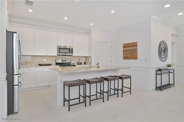 a kitchen with stainless steel appliances granite countertop a refrigerator a stove top oven a sink and a island