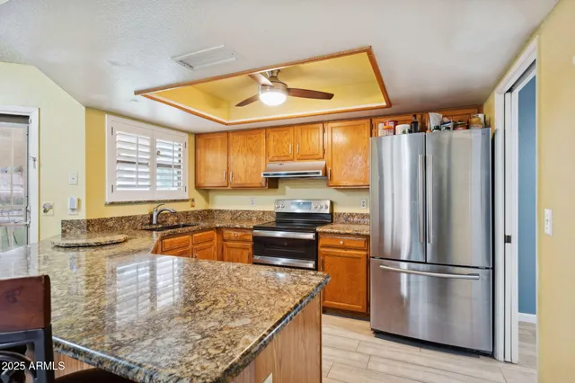 a kitchen with stainless steel appliances granite countertop a refrigerator a sink a stove and island