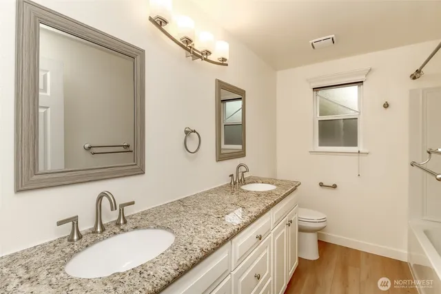 a bathroom with a granite countertop sink toilet and mirror