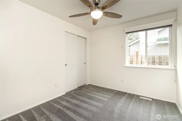 an empty room with a window and a fan