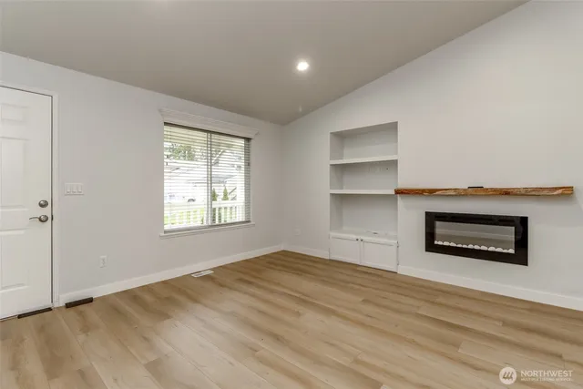 a view of empty room with a fireplace and wooden floor