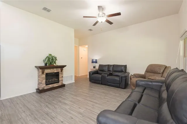 a living room with furniture a ceiling fan a lamp and a window