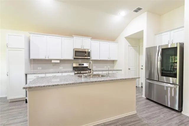 a kitchen with granite countertop white cabinets and stainless steel appliances