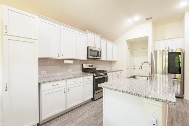 a kitchen with stainless steel appliances granite countertop a stove a sink and a microwave