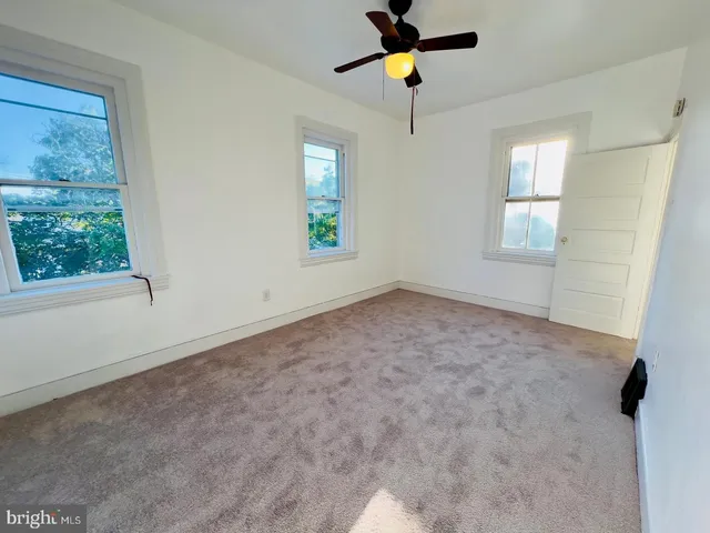 an empty room with windows and ceiling fan view