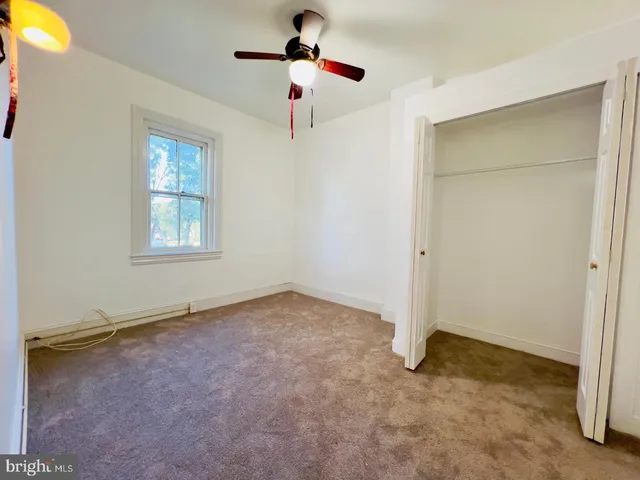 an empty room with ceiling fan and window