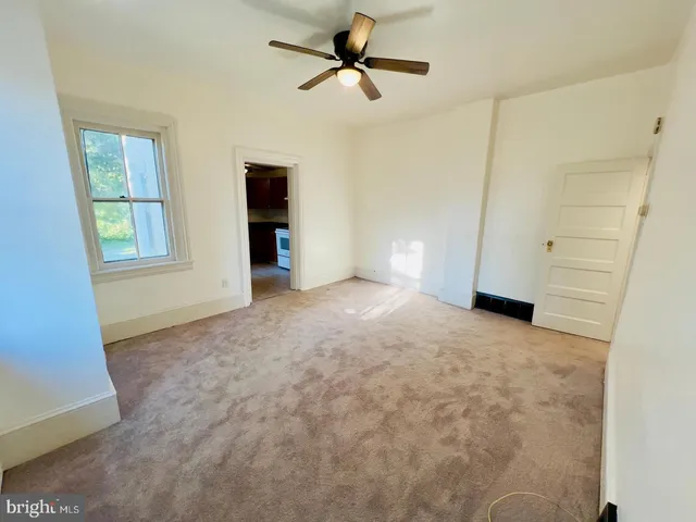 an empty room with windows and fan