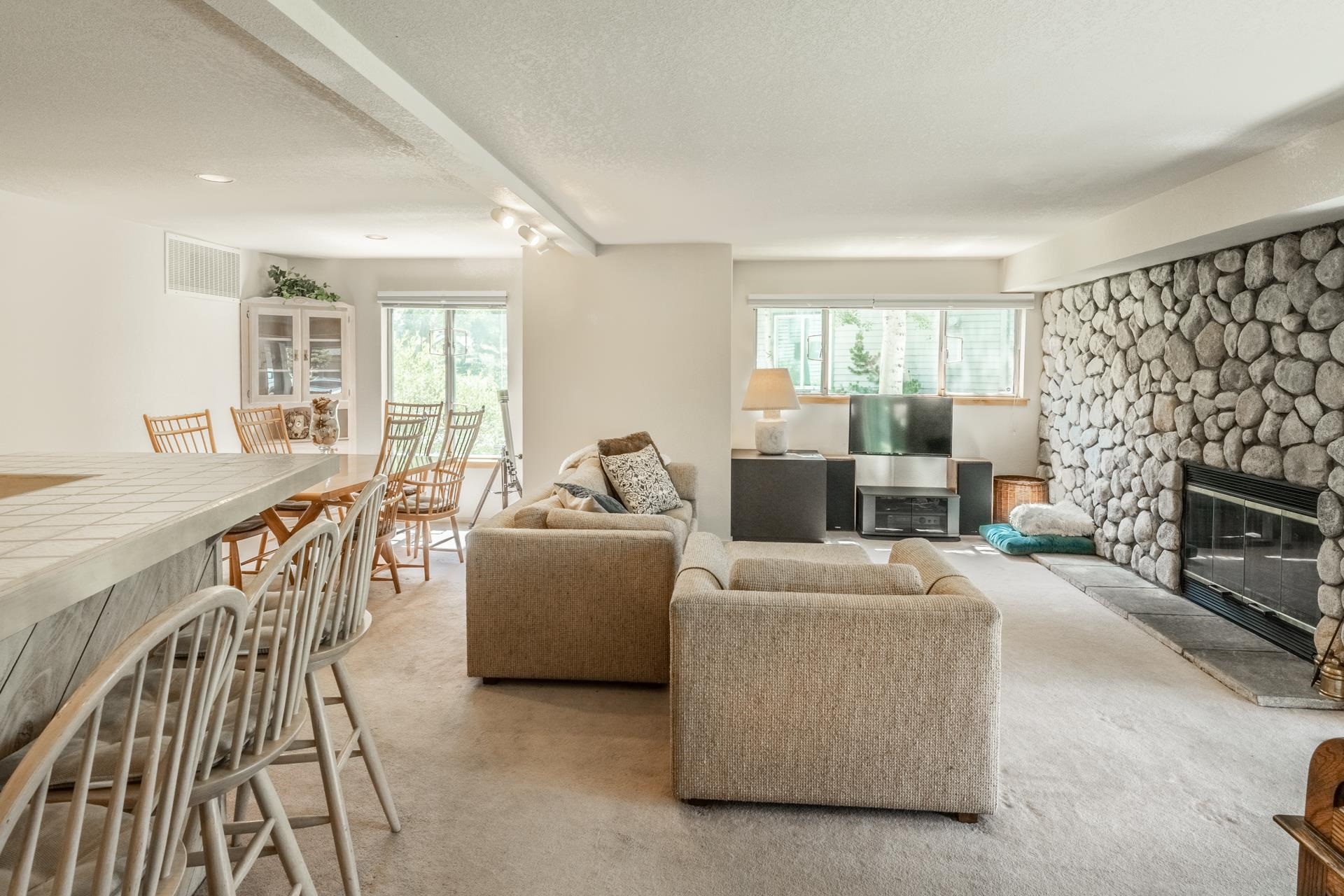 609 Golden Creek Road, Unit 609 Mammoth Lakes, CA 93546 - Photo 29 of 42 Spacious living area featuring a full-wall stone fireplace with a stone hearth, an expansive tiled bar area, and recessed lighting