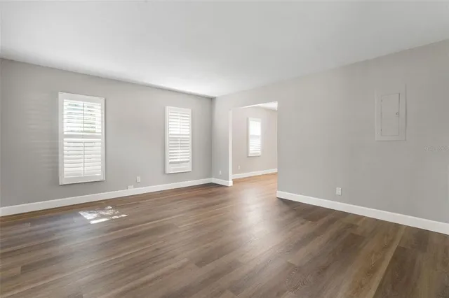 an empty room with wooden floor and windows