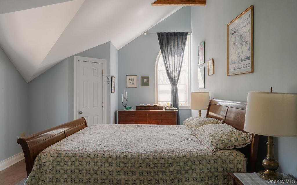 92 Fiddlers Bridge Road Staatsburg, NY 12580 - Photo 9 of 32 Sloped ceilings with exposed beam, arched window with opaque glass, light blue painted walls, white trim, and wood-finish flooring