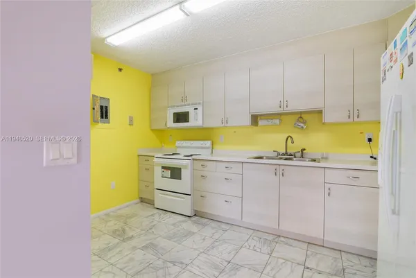 a kitchen with white cabinets and white appliances