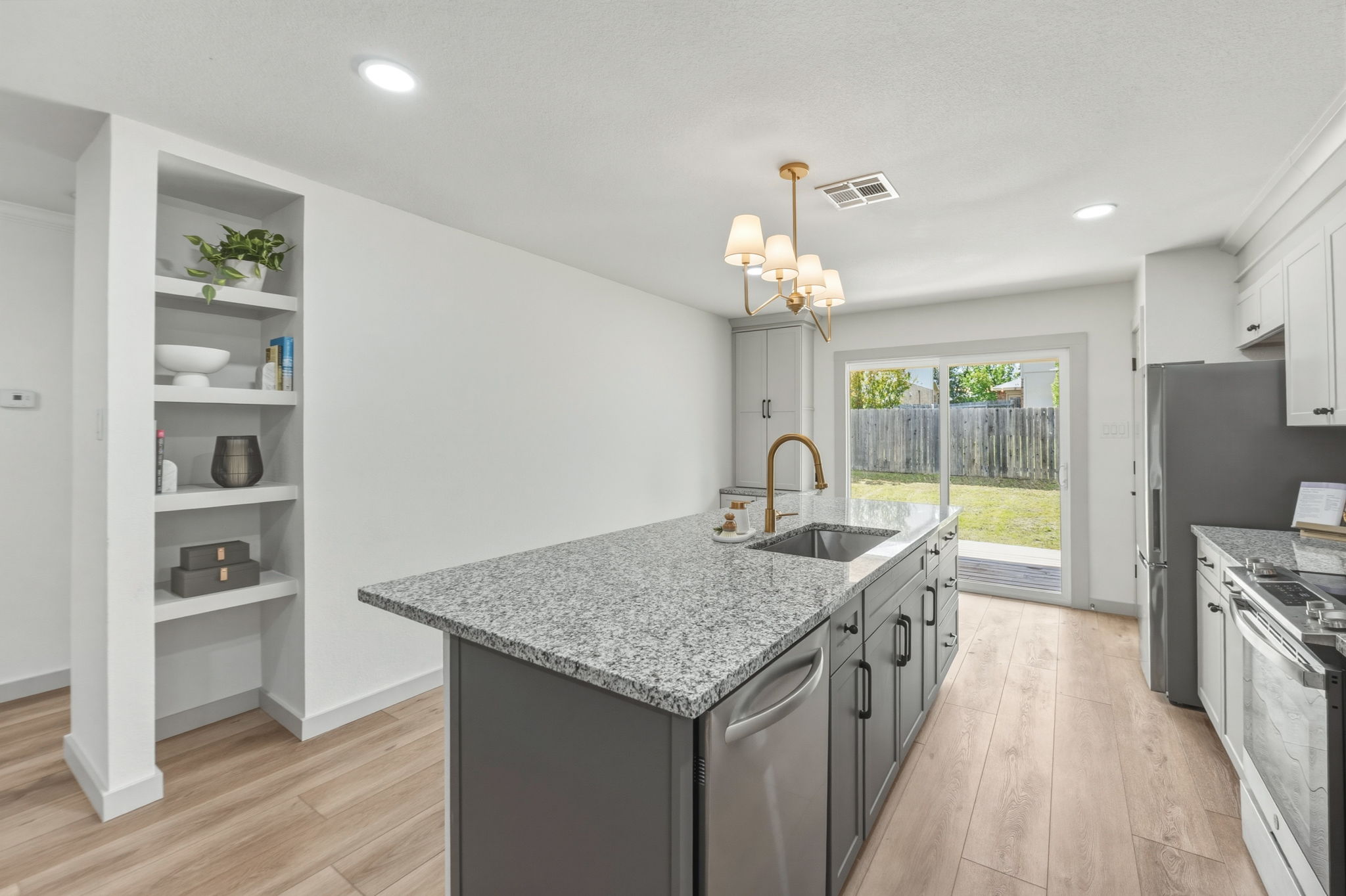 211 Banner Avenue Leander, TX 78641 - Photo 1 of 27 a kitchen with granite countertop a stove a sink and dishwasher with wooden floor