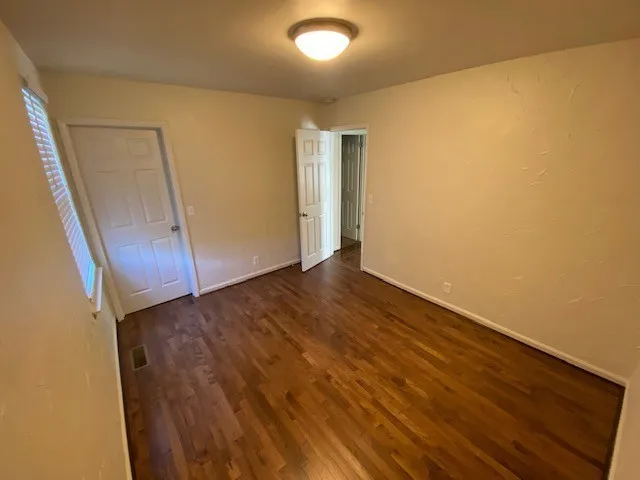 an empty room with wooden floor and entrance