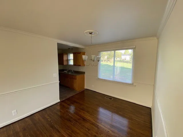 an empty room with wooden floor cabinet and windows