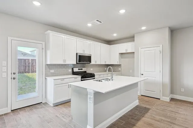 a kitchen with a sink a stove a refrigerator and white cabinets