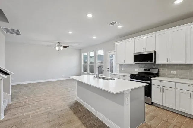 a large white kitchen with a sink and dishwasher stove top oven