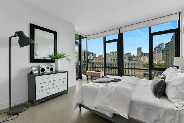 a bedroom with a bed and large windows