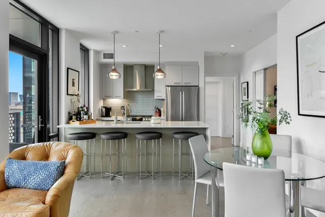 a kitchen with stainless steel appliances granite countertop a table chairs and a refrigerator
