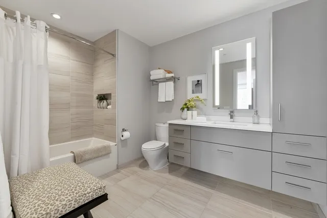 a bathroom with a granite countertop toilet sink and mirror