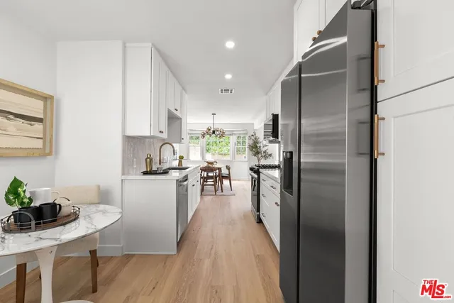 a kitchen with kitchen island a counter top space a sink stainless steel appliances and cabinets
