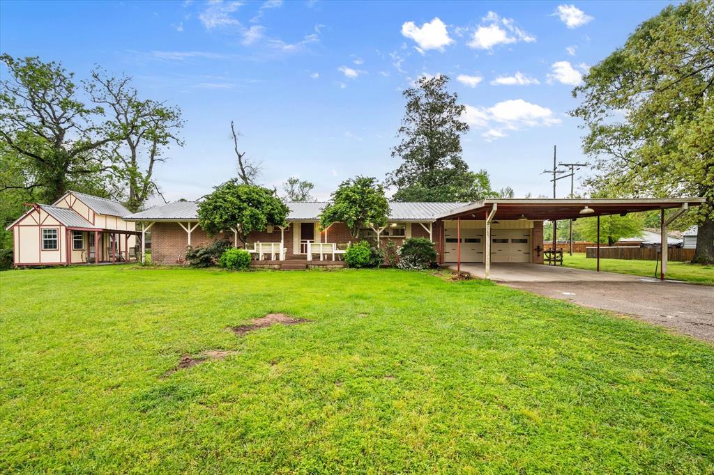 View of front of property featuring driveway, a front lawn, metal roof, a carport, and a garage