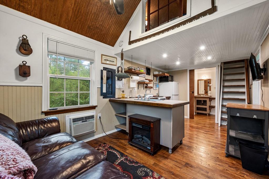 14036 Old Texaco Road Conroe, TX 77302 - Photo 20 of 40 Living area featuring lofted ceiling, wood ceiling, hardwood / wood-style flooring, a wall mounted air conditioner, and wainscoting