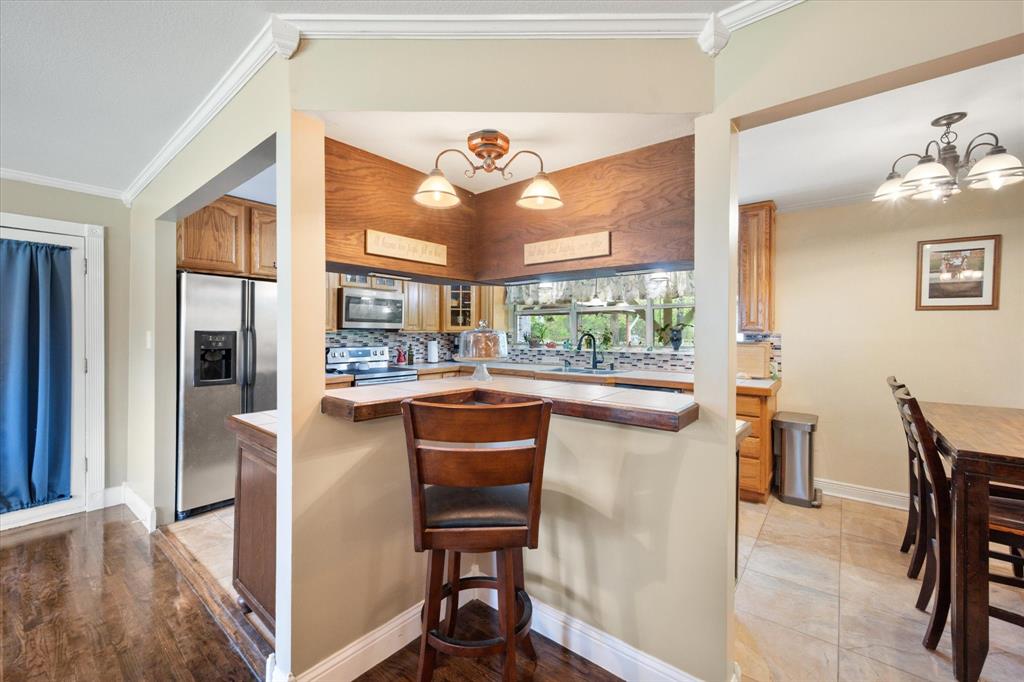 14036 Old Texaco Road Conroe, TX 77302 - Photo 5 of 40 Kitchen featuring crown molding, a sink, a chandelier, appliances with stainless steel finishes, and decorative backsplash