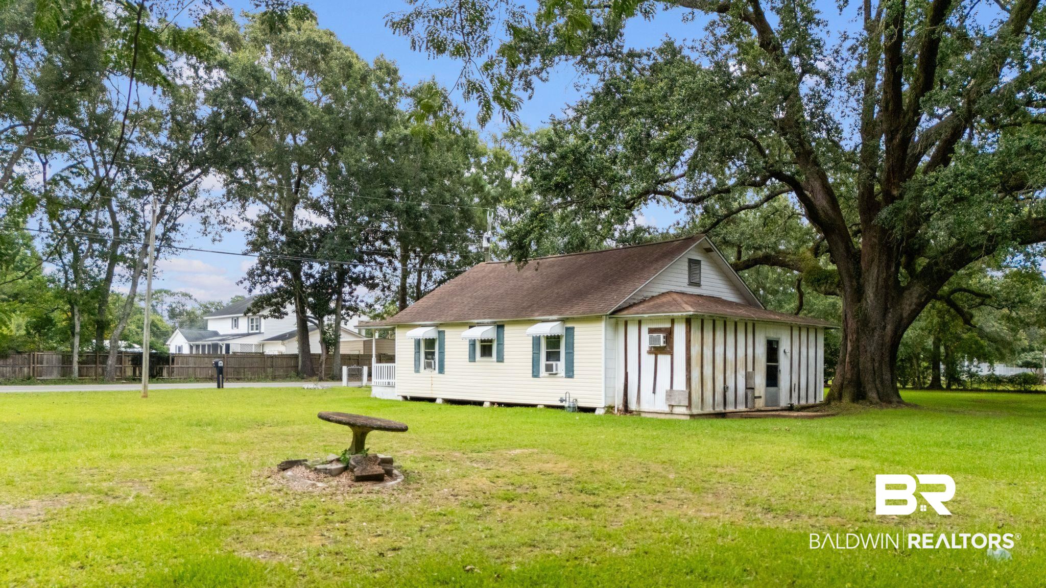 615 West Section Avenue Foley, AL 36535 - Photo 22 of 40 Expansive yard featuring a mature oak tree, a concrete birdbath, and a white-sided residence with green shutters