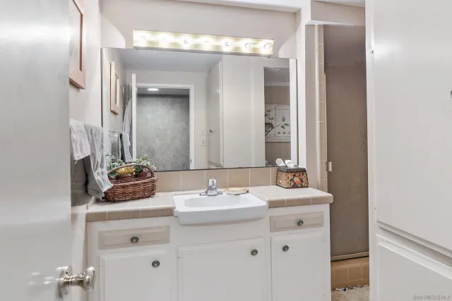 a spacious bathroom with a granite countertop sink a mirror and a shower