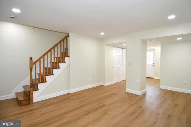 a view of an empty room with wooden floor and stairs