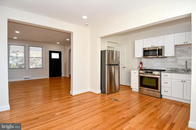 a kitchen with stainless steel appliances white cabinets a sink and a stove
