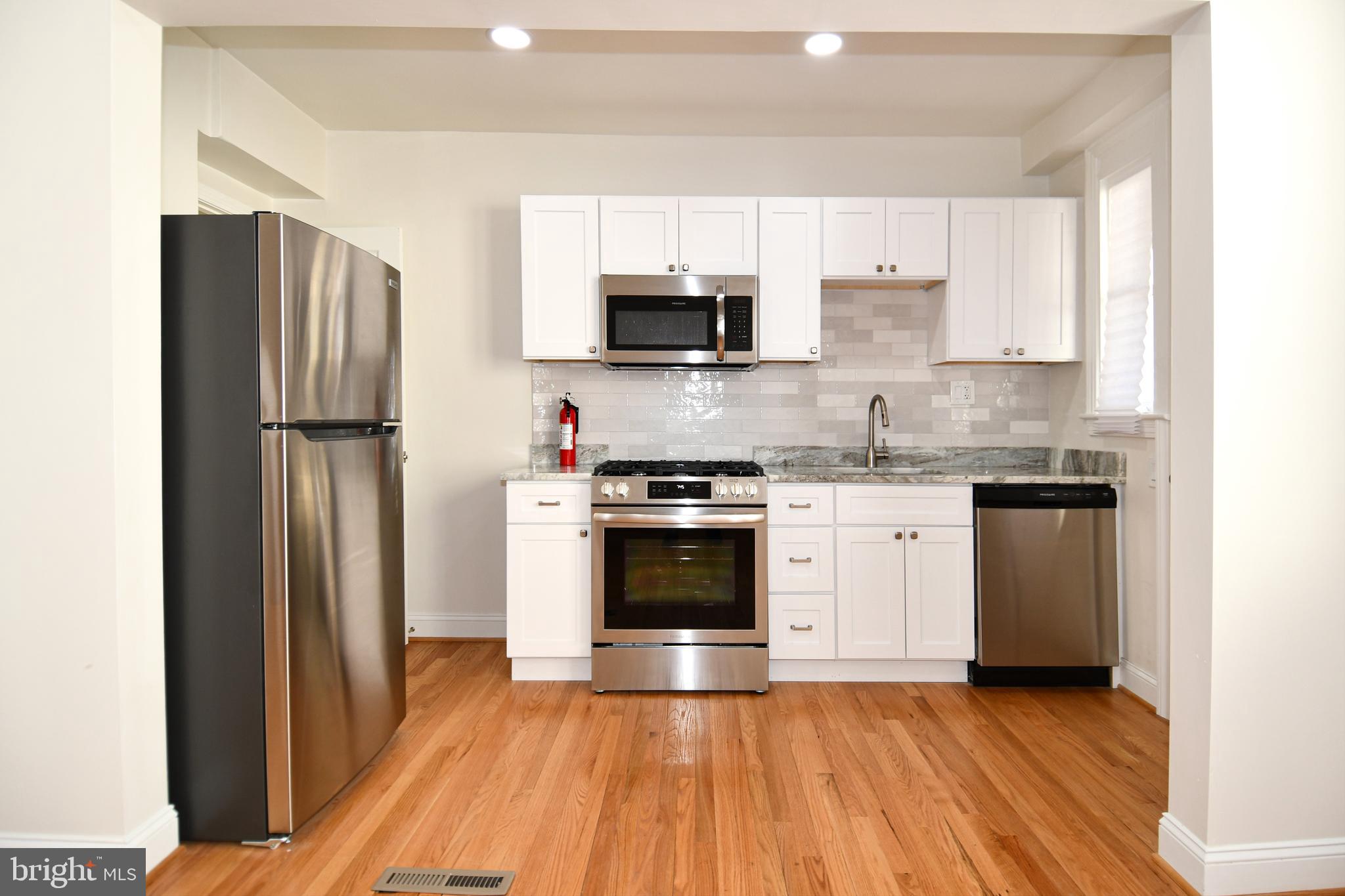 4620 Sargent Road Northeast Washington, DC 20017 - Photo 8 of 34 a kitchen with granite countertop a refrigerator stove and white cabinets