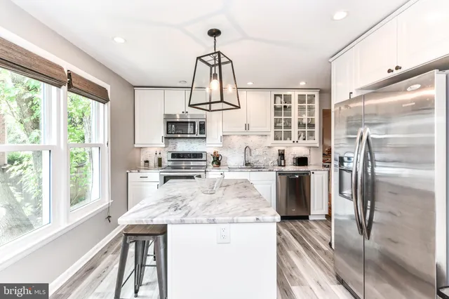 a kitchen with kitchen island a large counter top space a sink stainless steel appliances and cabinets