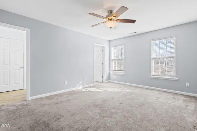 an empty room with windows and fan
