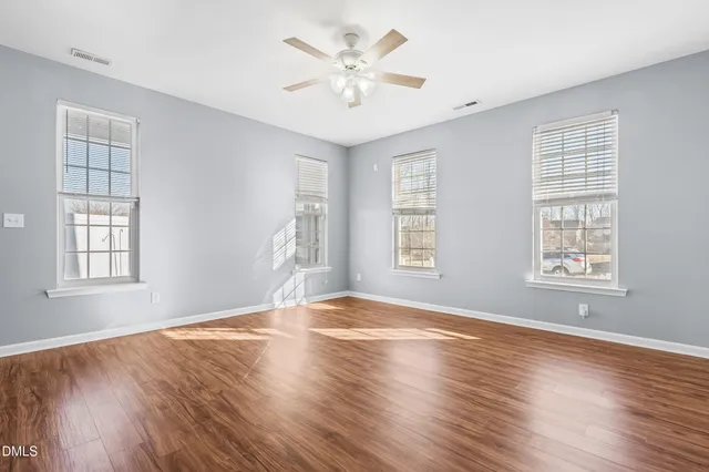 an empty room with wooden floor and windows