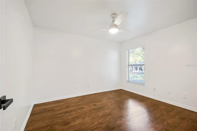 a view of empty room with wooden floor and fan