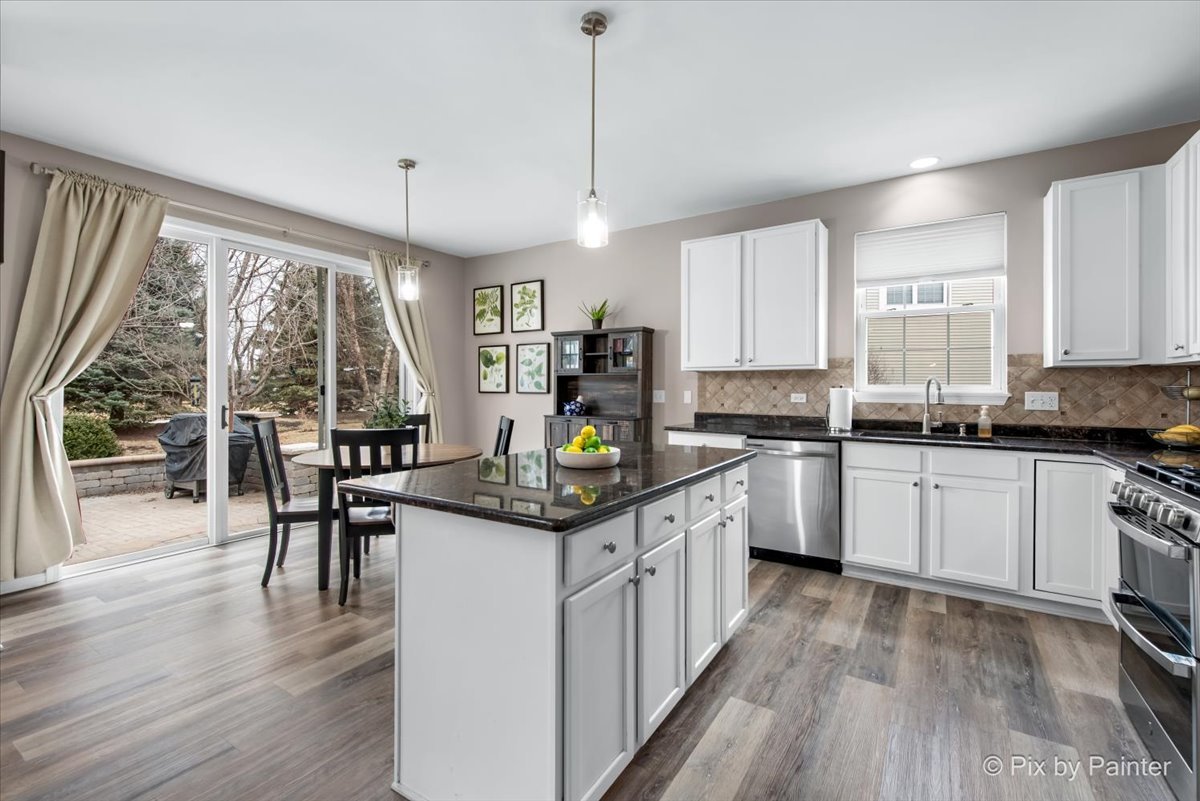 26428 Rustling Birch Way Plainfield, IL 60585 - Photo 4 of 49 a kitchen with kitchen island granite countertop a stove a sink a center island and windows